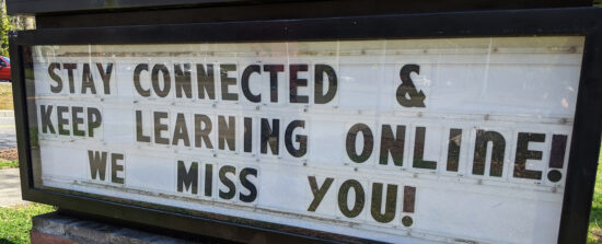 A message board outside of a school, stating, “Stay connected & keep learning online! We miss you!”