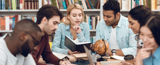 A multiethnic group of students study together at a library.