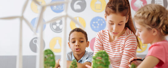Children work on a project with model-sized trees and wind turbines.
