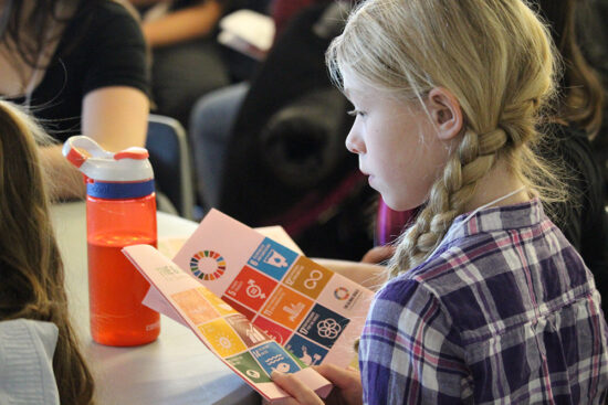 Une fille lit un livret qui contient une liste des objectifs de développement durable.