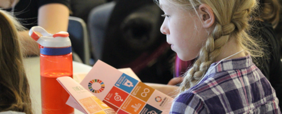 A girl reads a booklet with containing a list of the Sustainable Development Goals.