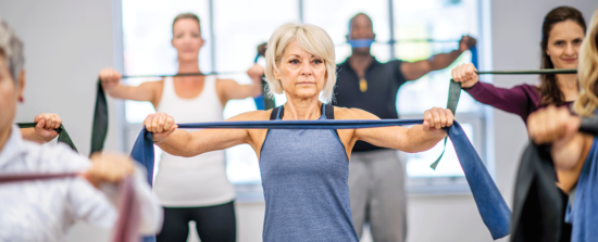 Mature women exercising with people in the background